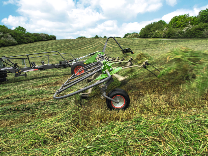 Fendt Twister sprer gras på et jorde. Gresset kastes opp i luften.