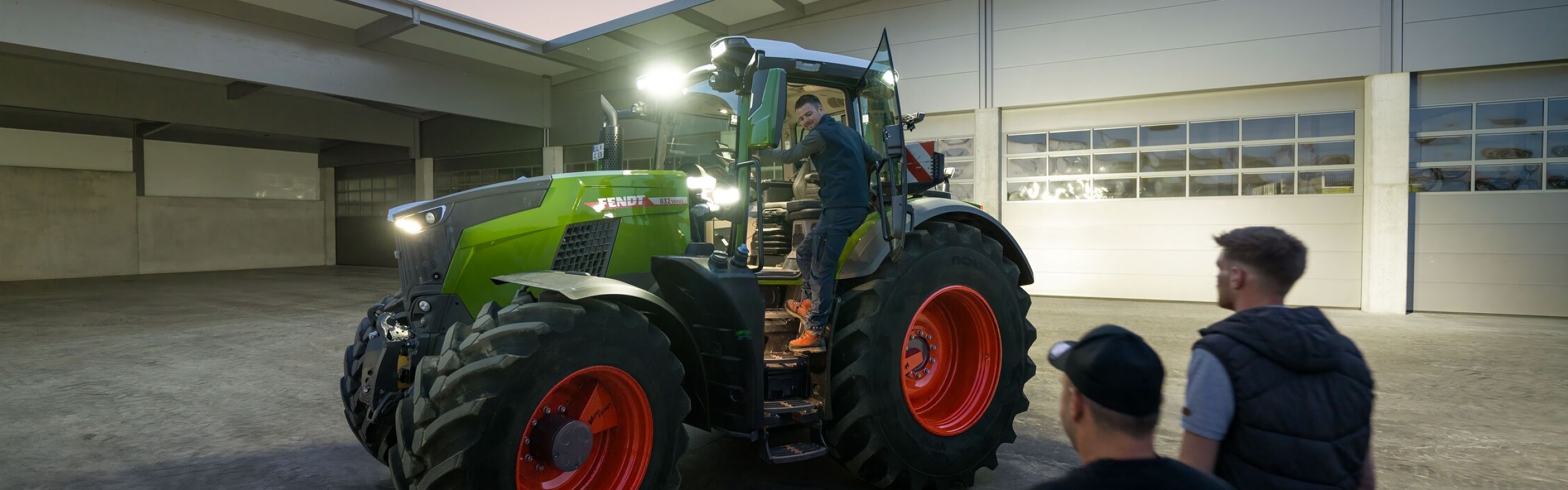 Blikk inn på gårdsplassen til en en maskinentreprenør med en Fendt 800 Vario traktor med full belysning klar for føreren