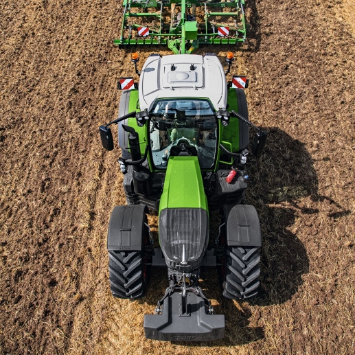 Et fugleperspektiv av en Fendt 700 Vario Gen7.1 på et jorde. Den grønne traktoren kjører over bakken og trekker et påmontert jordbearbeidingsredskap etter seg.