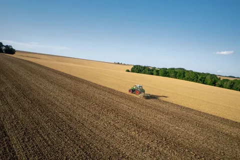 Zielony Fendt 800 Vario uprawia obszar za pomocą brony talerzowej Amazone, zdjęcie zrobione z perspektywy lotu ptaka.