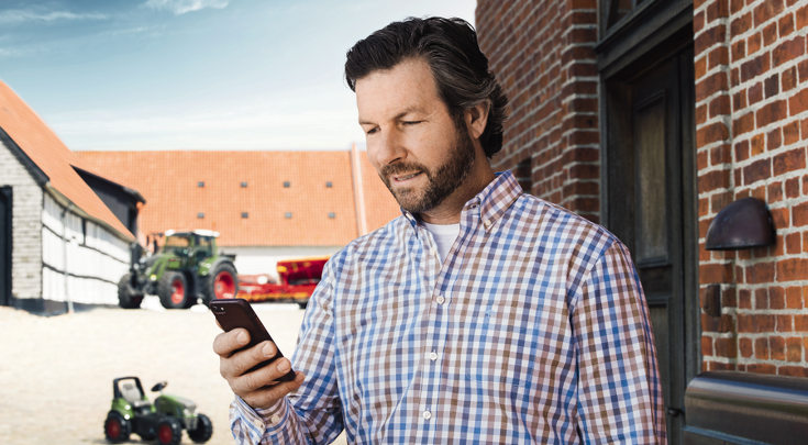 Ciemnowłosy mężczyzna w średnim wieku korzysta z mobilnej transmisji danych Fendt Connect