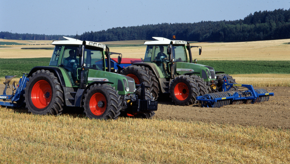 Historia Fendt 700 Vario Dwa starsze ciągniki Fendt jadą obok siebie na polu.