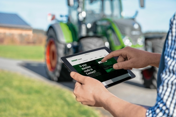 Fendt Connect - centralne rozwiązanie telemetrii dla maszyn Fendt Zbliżenie tabletu w rękach rolnika, który sprawdza swoje kluczowe dane maszynowe za pomocą Fendt Connect. W tle widać lekko rozmytą zieloną traktor marki Fendt.