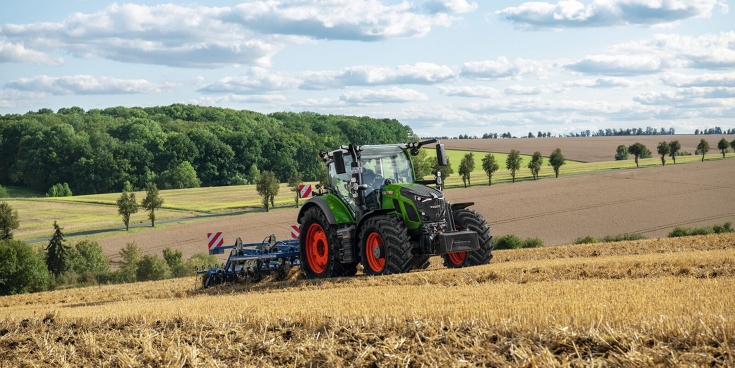 Zielony ciągnik Fendt 620 Vario, wyposażony w narzędzie, przejeżdża przez ściernisko, aby uprawiać glebę.