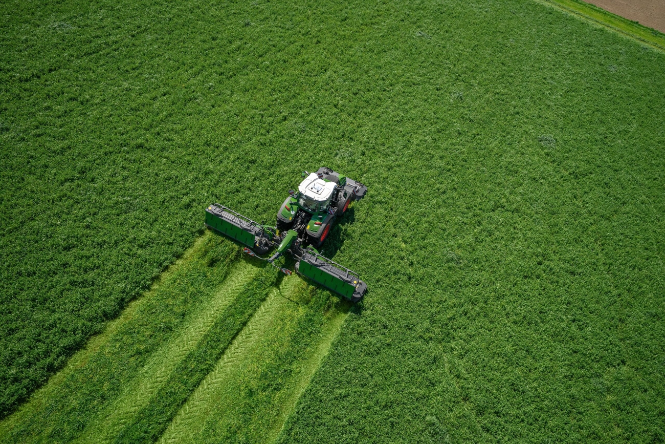 Ciągnik Fendt 800 Vario kosi łąkę Zielony ciągnik Fendt 800 Vario kosi na łące z zespołem koszącym, zdjęcie z lotu ptaka.