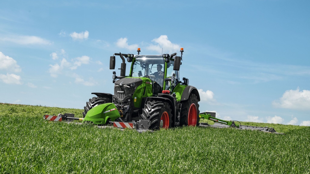 Rolnik prowadzi ciągnik Fendt 700 Vario Gen7 po łące i kosi kosiarką Fendt Slicer.