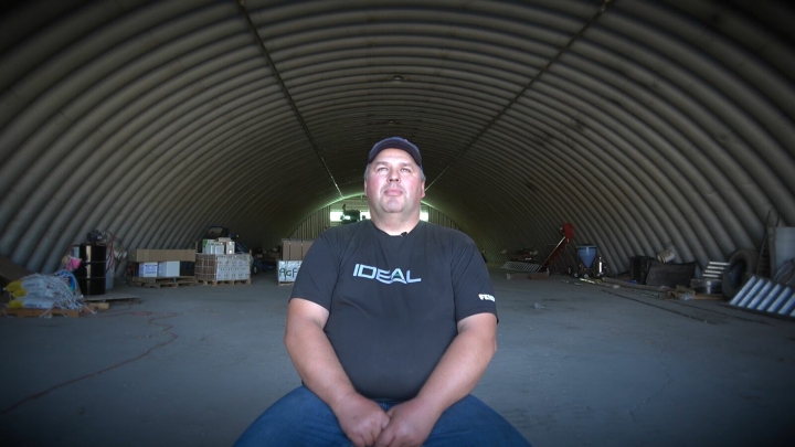 Retrato de un granjero en una gran nave, con una camiseta negra con la inscripción IDEAL.