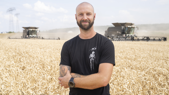 Retrato de Andrè Poese delante de un campo en el que cosechan dos cosechadoras Fendt IDEAL.