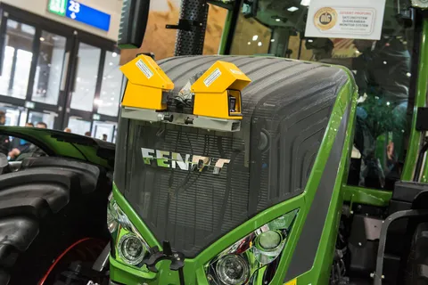 Närbild av det nya gula kamera-/monitorsystemet som presenteras i Fendt 828 Vario, med DLG-certifierat testmärke i bakgrunden på frontrutan.