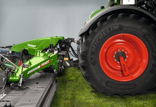 En Fendt-traktor med en Fendt Slicer-tallriksslåtter står på ett fält i skymningen.