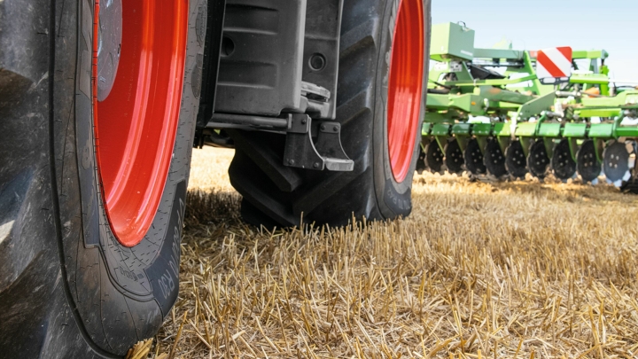 Närbild av ett skördat sädesfält och en Fendt 700 Vario som kör på det samtidigt som den skyddar jorden