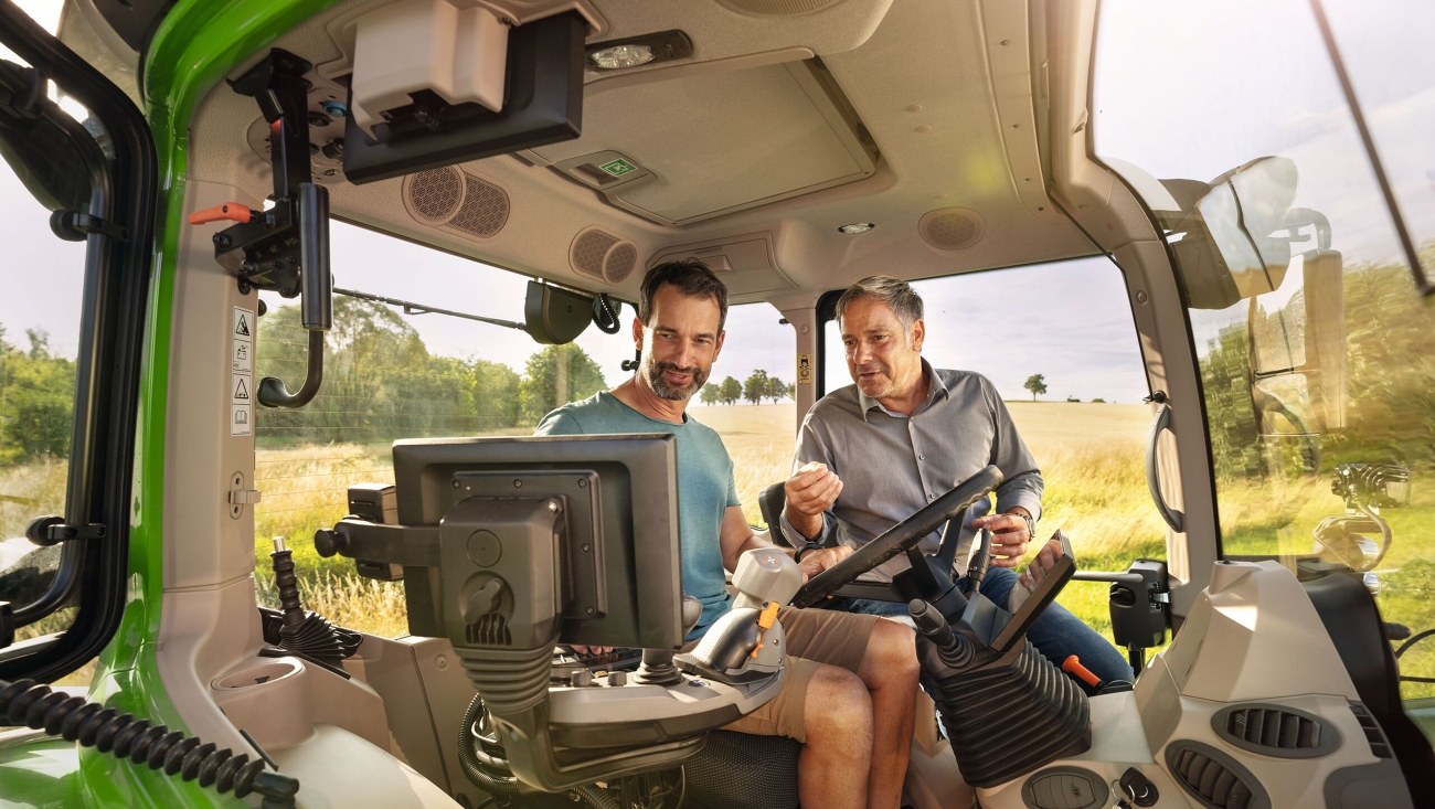Fendt Vorführservice für Kunden Ein Fendt Händler in der Kabine eines grünen Traktor-Vorführmodells von Fendt bei einem Landwirtskunden auf dem Gelände