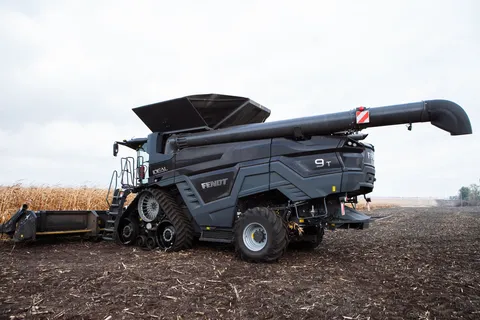 Вигляд збоку великого чорного комбайна Fendt IDEAL на полі. Праворуч — вже обмолочена ділянка коричневого поля, а комбайн стоїть перед рештою золотих колосків.