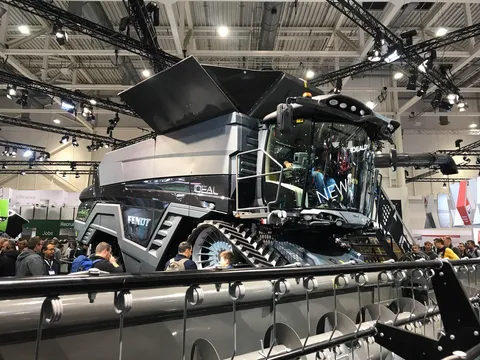 Бічний вигляд нового чорного Fendt IDEAL у виставковому залі Agritechnica, оточеного захопленими відвідувачами виставки