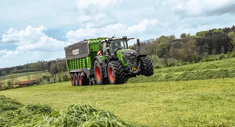 Трактор Fendt їде по зеленому полю з Fendt Tigo.