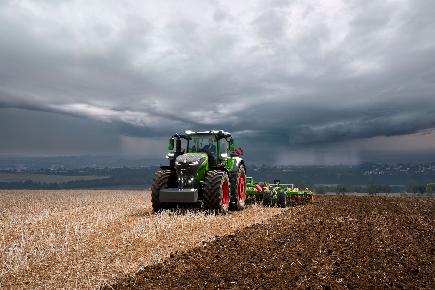 Трактор Fendt 1000 Vario усе ще працює в полі на повну потужність, незважаючи на важкі грозові хмари, що насуваються.