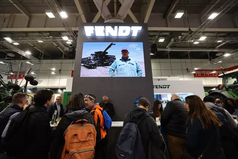 Visitors standing at the Fendt exhibition stand in front of a screen showing videos from Fendt