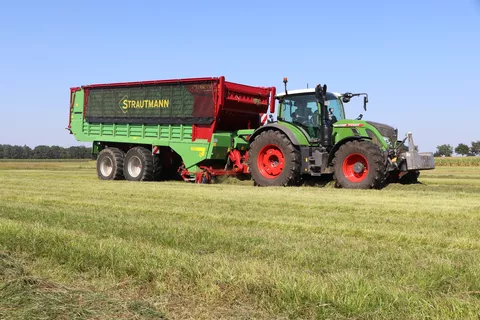 A Fendt tractor pulls a Strautmann loader wagon across a pasture