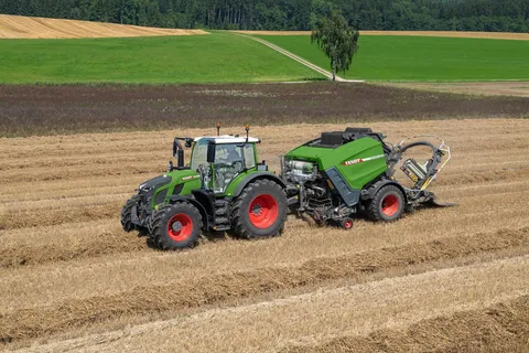 A Fendt Rotana V Combi round baler behind deposits round bales on a field.