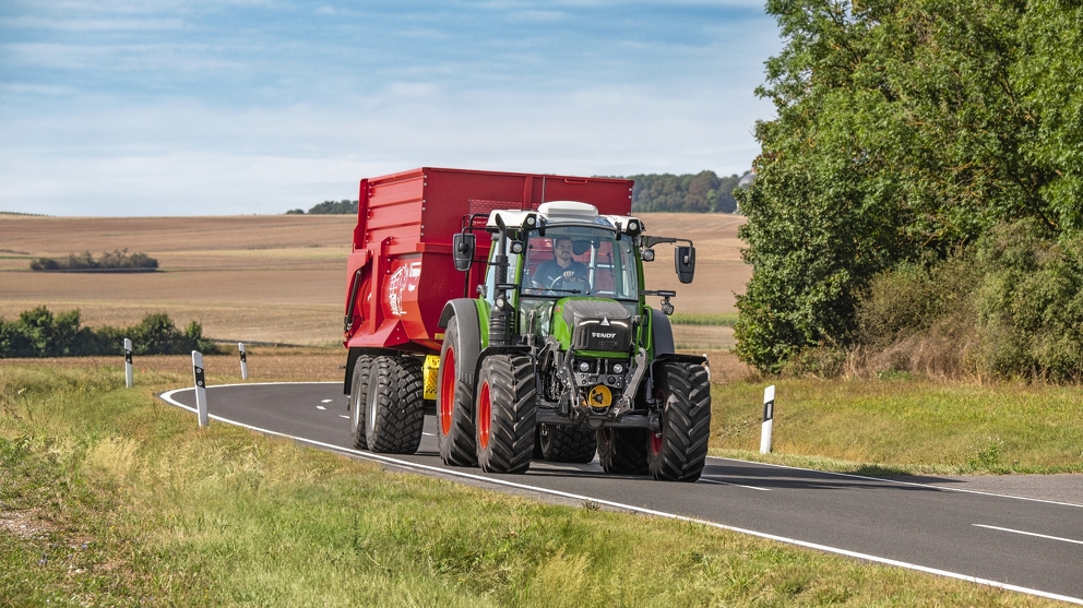 Farmer with Fendt 200 Vario and loader wagon on the road