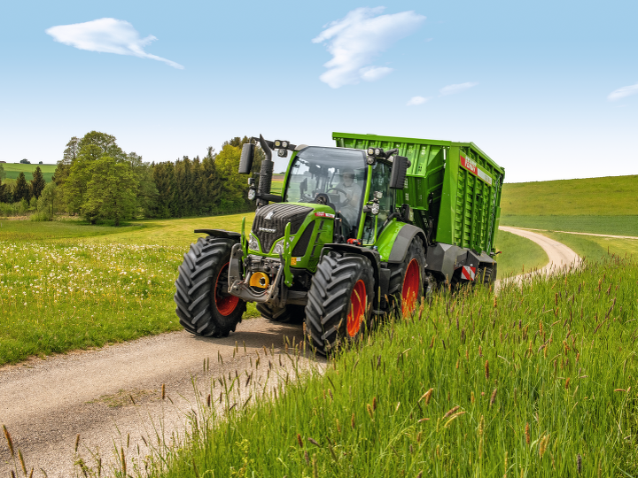 The new Fendt 500 Vario drives with loader wagon on a field path.