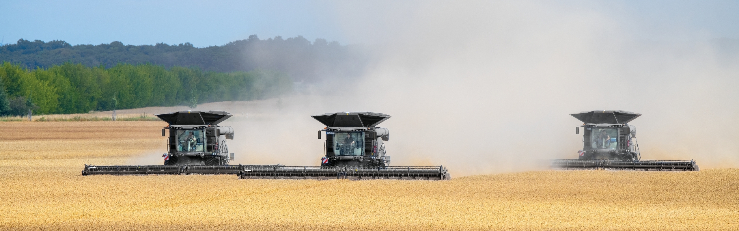 3 Fendt IDEAL models driving side-by-side in a wheat field