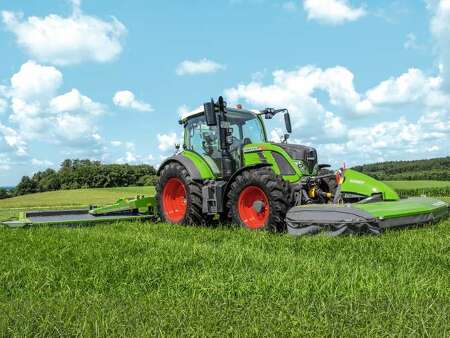 A farmer drives his tractor and a Fendt Cutter mower in the meadow