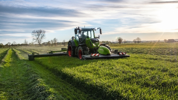 Fendt Cutter mower A farmer drives his tractor and a Fendt Cutter mower in the meadow