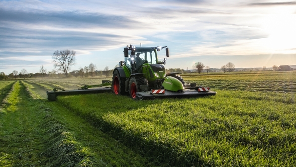 A farmer drives his tractor and a Fendt Cutter mower in the meadow