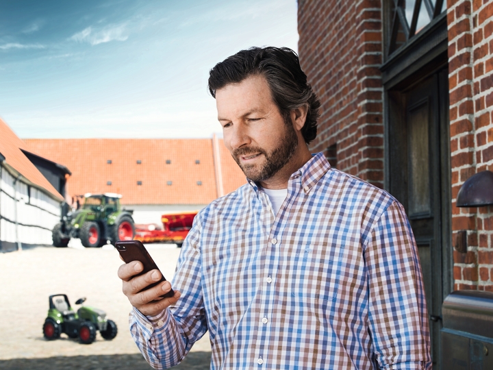 Customer with smartphone, Tractors behind