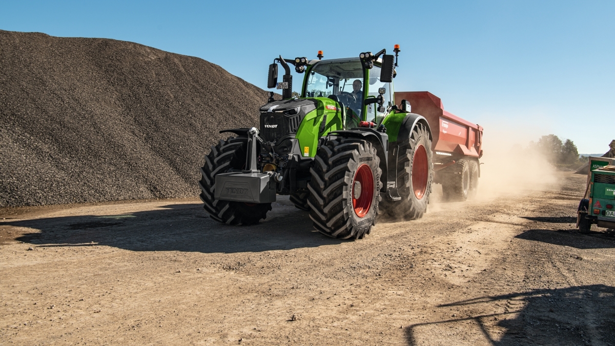 A farmer driving a Fendt 700 Vario Gen7 and a red Krampe tipper.