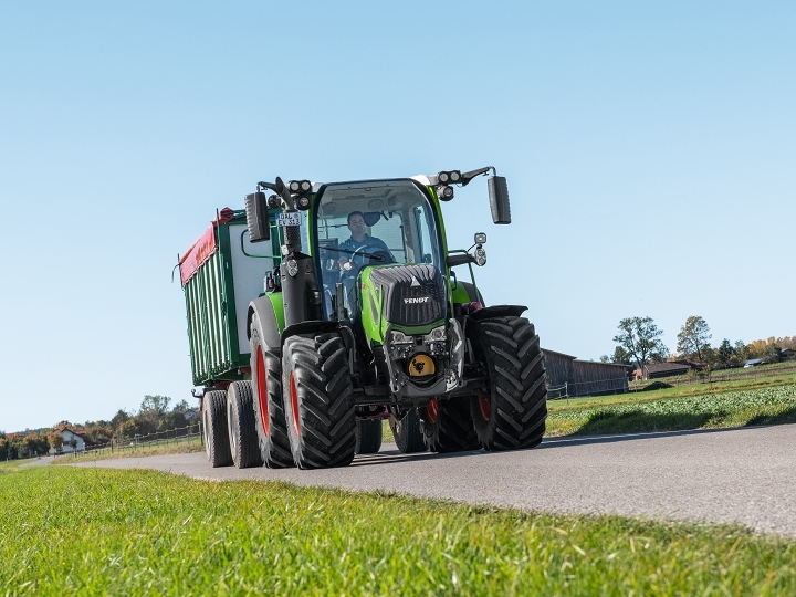 A farmer drives his Fendt 300 Vario and a loader wagon on the road.