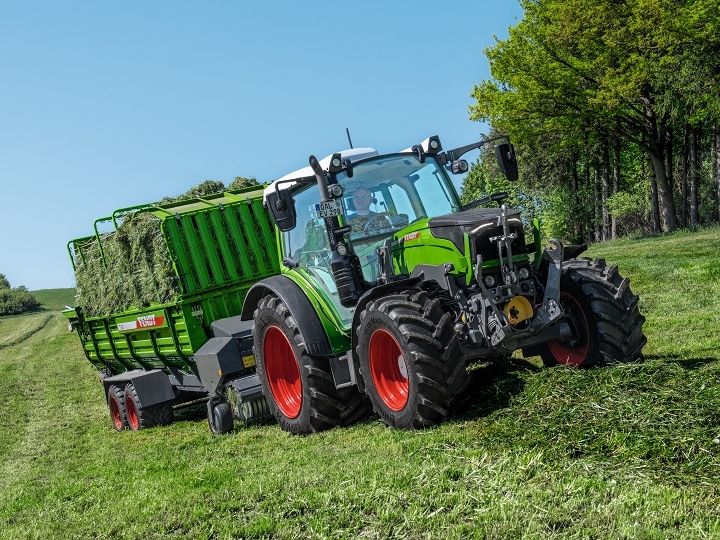 A farmer drives his Fendt 200 Vario and a Fendt Tigo loader wagon in the meadow.