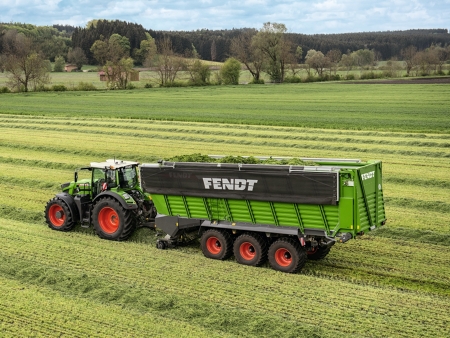 A Fendt tractor with Fendt Tigo combi rotor wagon collecting grass swathes on meadow