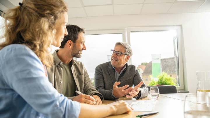 A farmer and his wife sit in the office of a Fendt dealer and get advice.