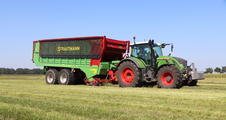 A Fendt tractor pulls a Strautmann loader wagon across a pasture