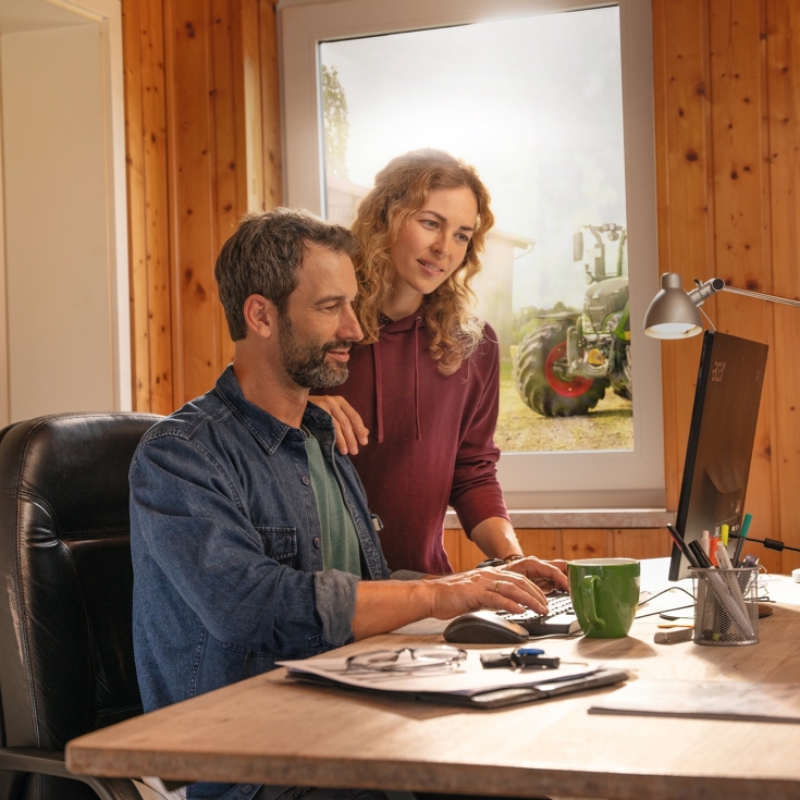 A farmer couple in front of their office computer, creating field boundaries with FendtONE Agronomy.