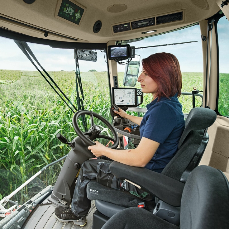 A farmer sits in her Fendt Katana and steers the machine through a maize field.