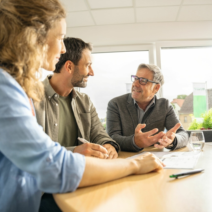 Two farmers sit at a table with a Fendt dealer and get advice.