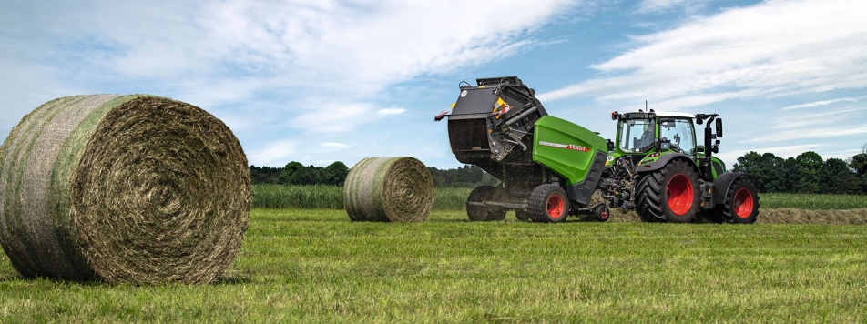Fendt Rotana V round baler A Fendt tractor with a Fendt Rotana V round baler attached travelling in a field on the horizon, with two ready-baled round bales in front of it