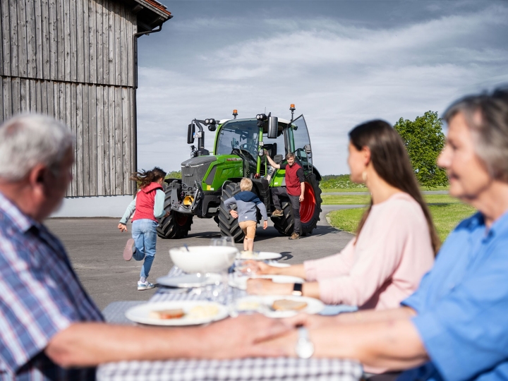 The family sits at the dining table on their farm and  are thrilled about the arrival of the last two family members: the farmer and the Fendt 300 Vario