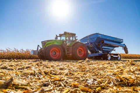 Fendt 1000 Vario Tractor pulling a grain cart in corn field