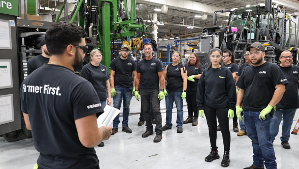 A Group of 10 Assembly Line Workers Meeting in the Factory with Fendt Equipment in the Background
