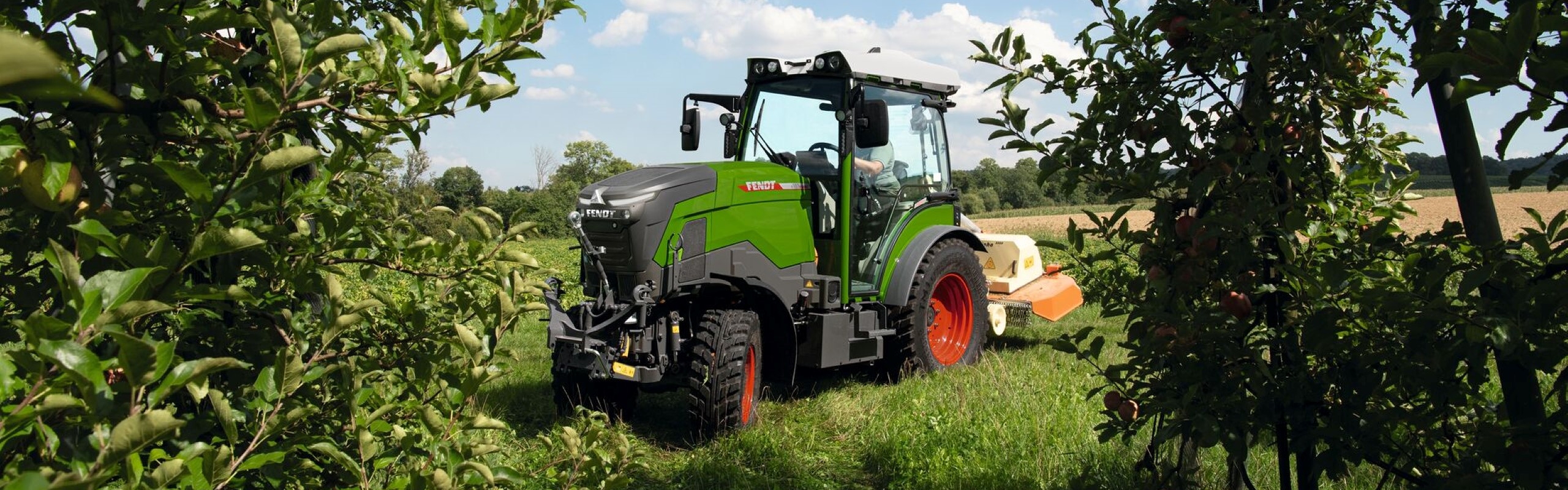 Fendt e100 Vario in a field with bushes on each side of the tractor