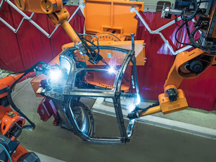 Industrial robots weld precisely on a tractor cab frame in an automated production line.