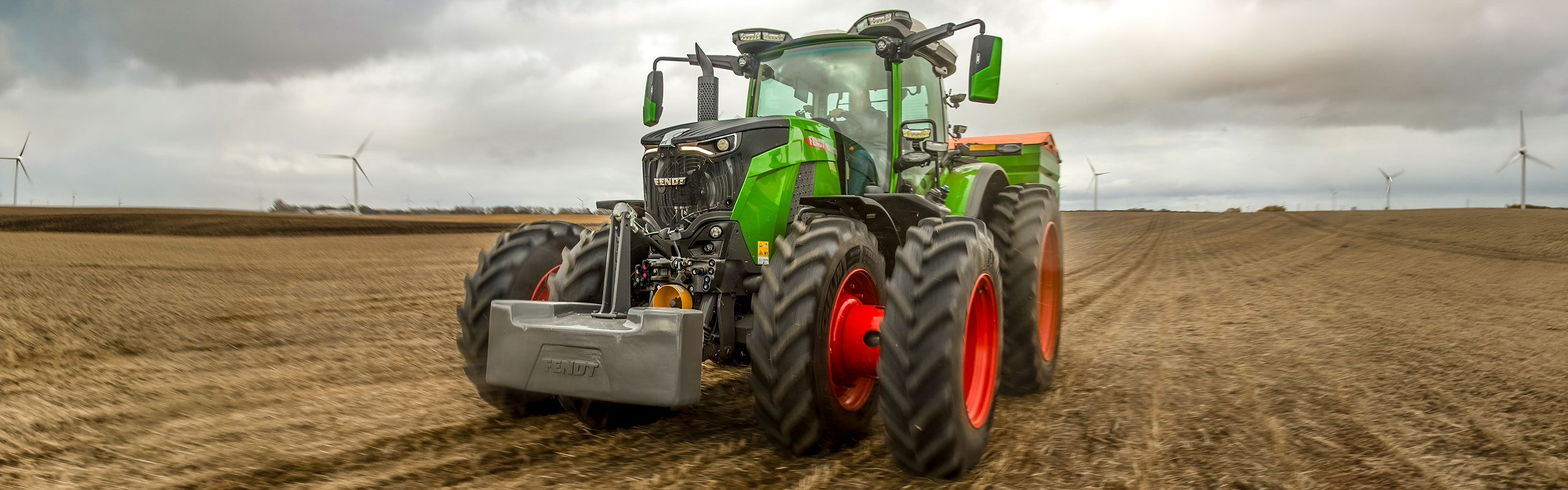 Fendt 800 Vario Gen5 with dual wheels in a field with windmills in the background