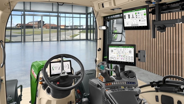 Inside the cab of a Fendt 500 Vario Gen4 with beige interior, black driver's seat and several digital displays. The steering wheel centred in front of a dashboard. To the right is the armrest with crossgate lever and controls. A tablet holder with terminal is mounted on the front window. The large glass surface shows a modern hall with wooden cladding and panoramic windows.