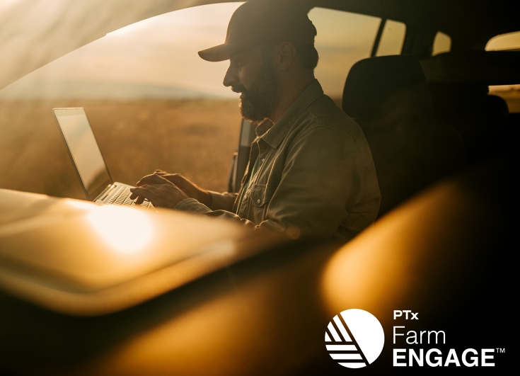 Farmer in his truck on laptop at sunset with golden rays of light around him