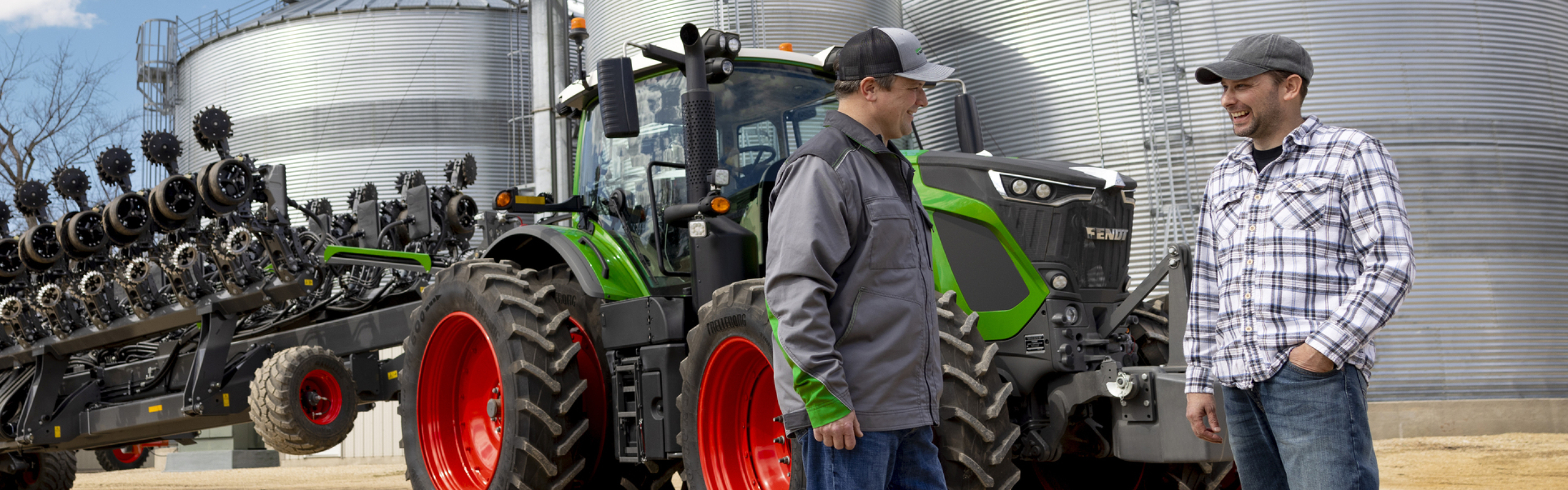 Fendt Farmer meets with Fendt Technician on his farm with Fendt tractor and Fendt Momentum and grain bins in the background