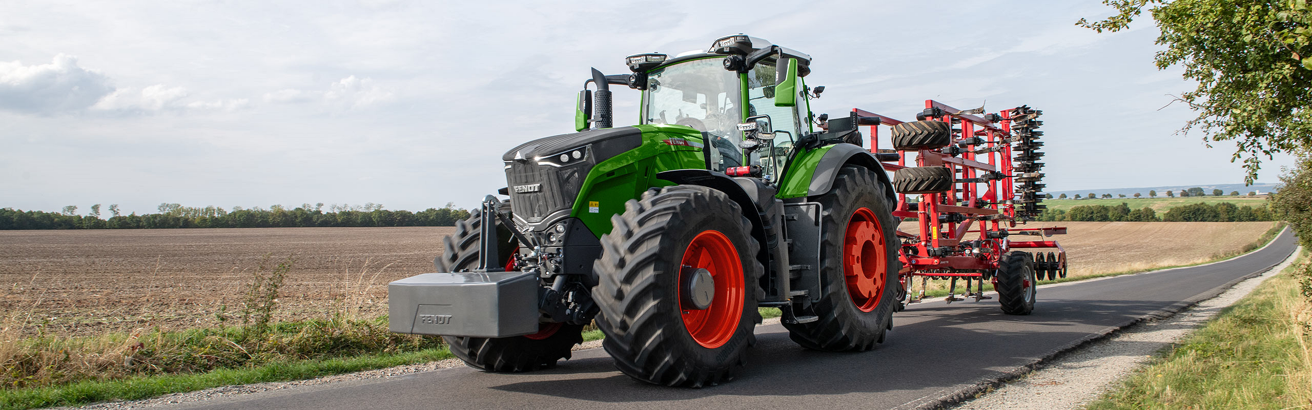 Fendt 1000 tractor pulling tillage down a small country road